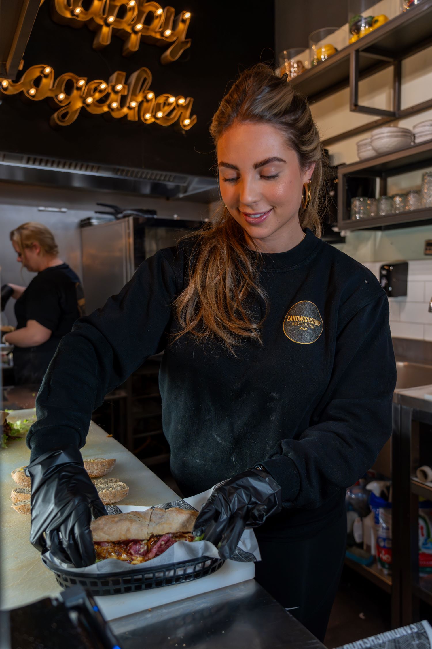 Medewerkster die een broodje aan het maken is